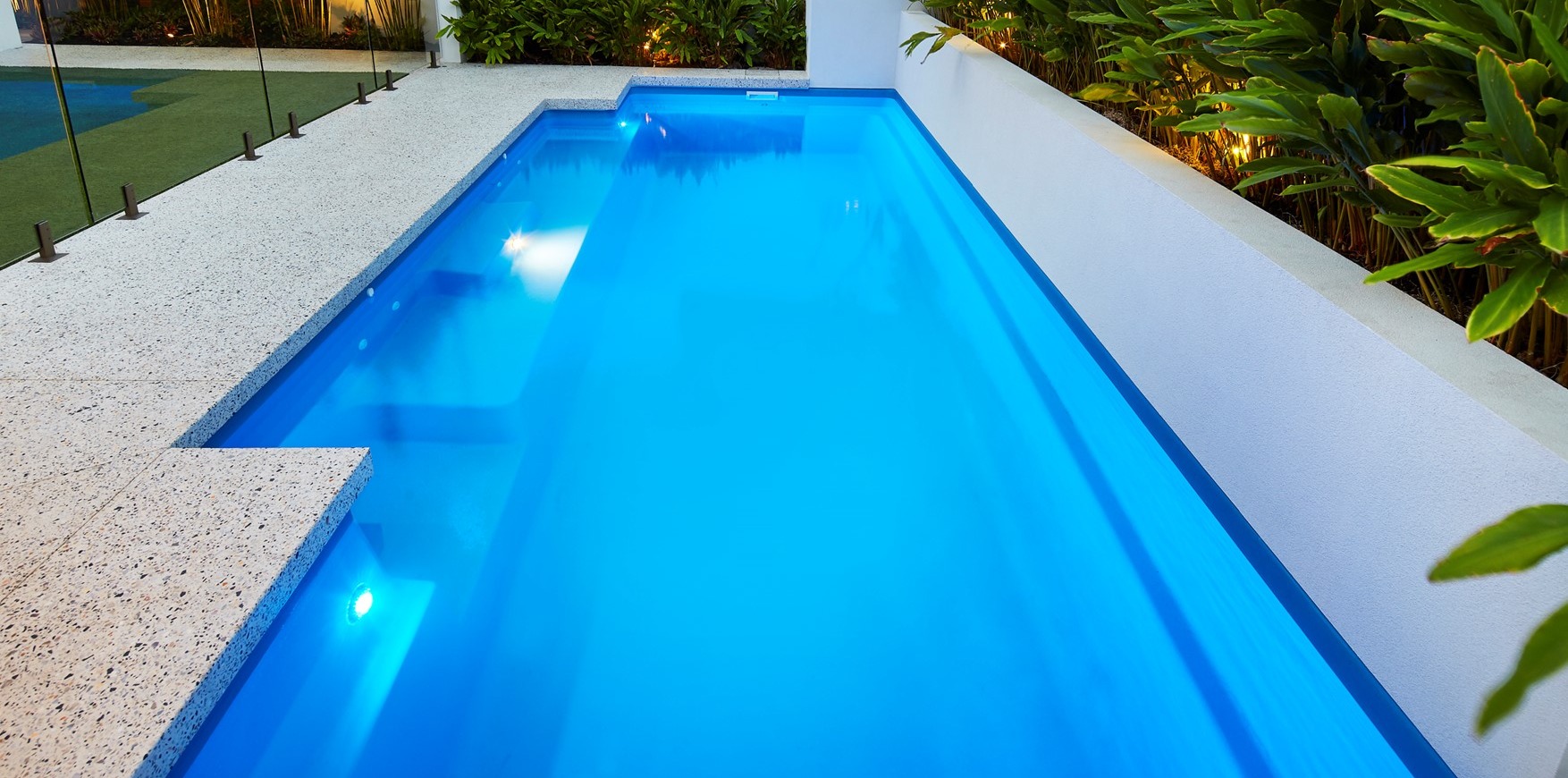 Venice Slimline pool illuminated in a narrow landscaped backyard